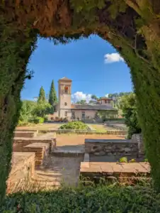 View of the historic watchtower and high gardens of the Generalife, framed by cypress trees, in the Alhambra, Granada