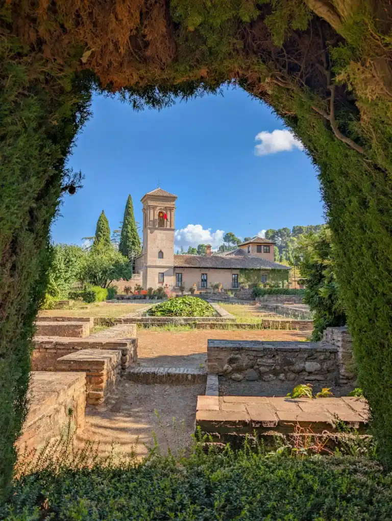 View of the historic watchtower and high gardens of the Generalife, framed by cypress trees, in the Alhambra, Granada