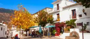 Street view of the white washed houses in Pampaneira, La Alpujarra, with colorful traditional carpets and handicrafts displayed outside.