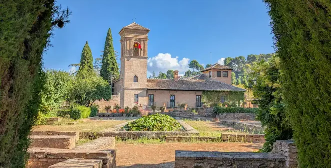 View of the historic watchtower and high gardens of the Generalife, framed by cypress trees, in the Alhambra, Granada